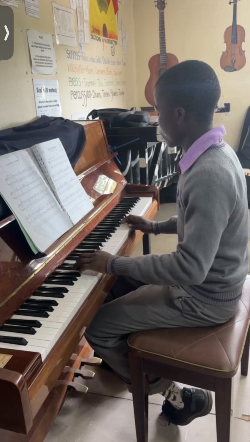 A student learning piano at the Jacaranda School